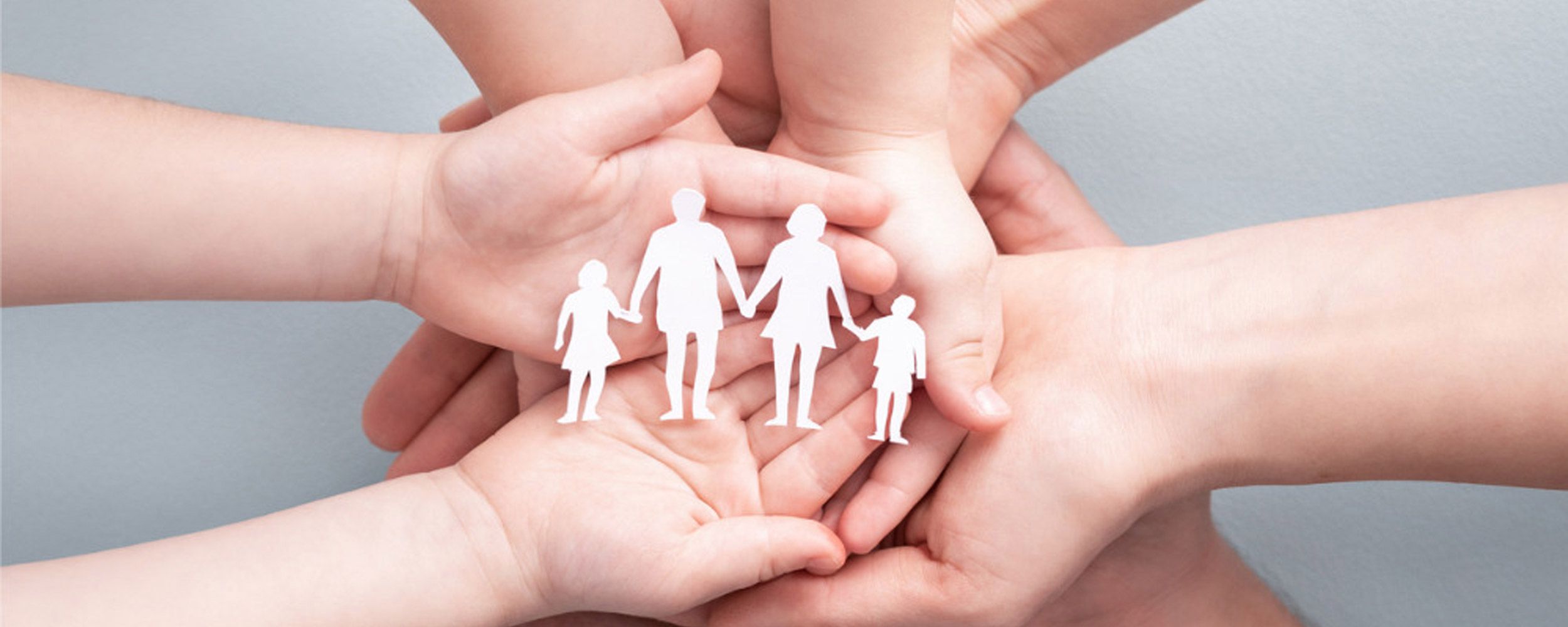 Hands of a family holding a paper cut out of a four person family. Atkinson Crehan Law Family Wills.