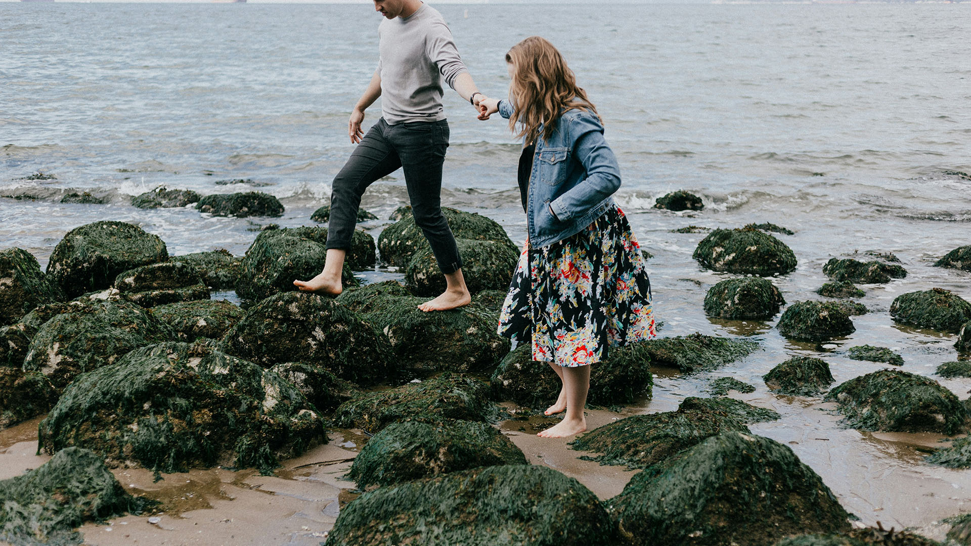 couple with contracting out agreement holding hands while walking over beach rocks